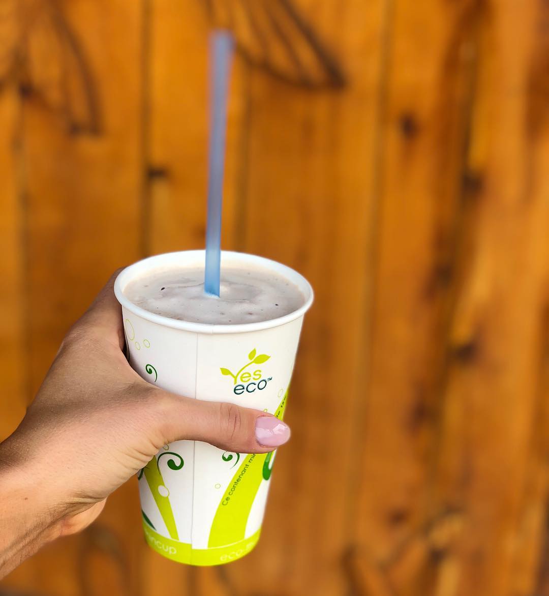 A customer holding up a tall ice cream cone outside the shop