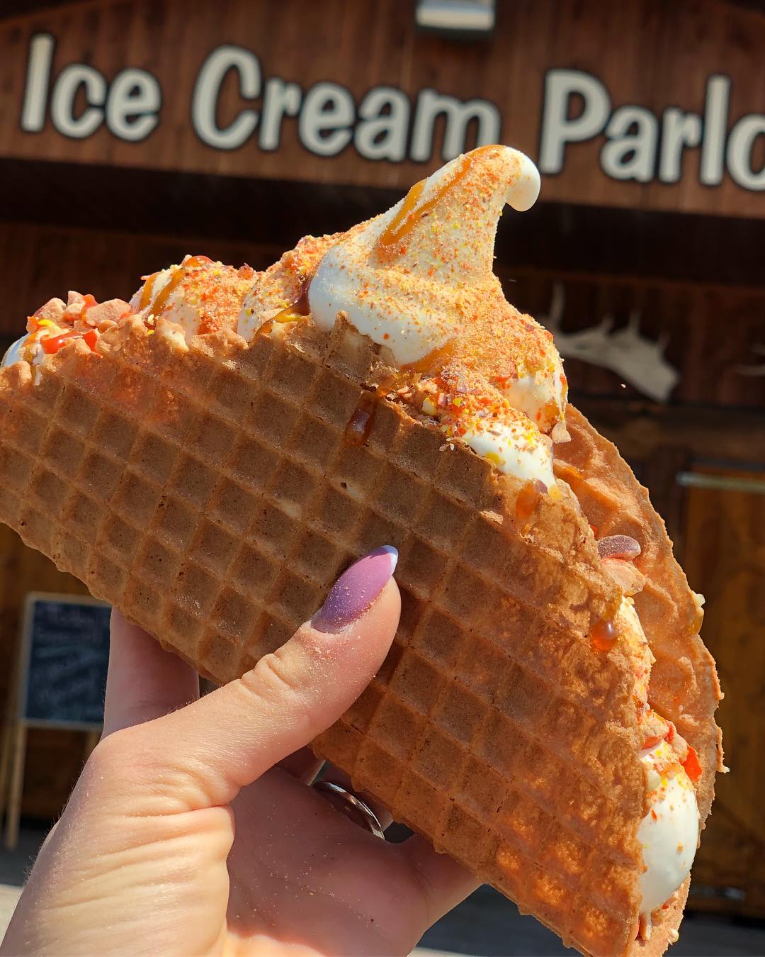 Close-up of a multi-scoop waffle cone against the log-cabin wall