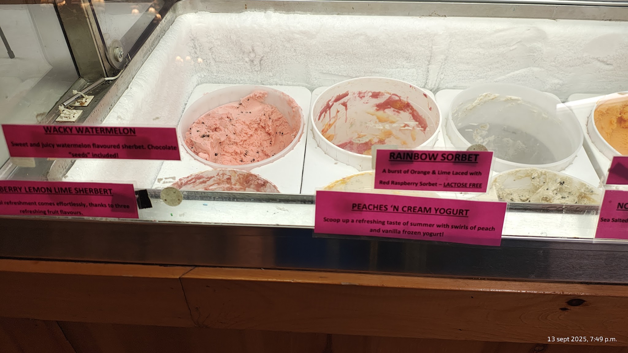 Bright sherbets and sorbets in the display case with hand-lettered pink labels reading Black Watermelon, Berry Lemonade, and Rainbow Sorbet